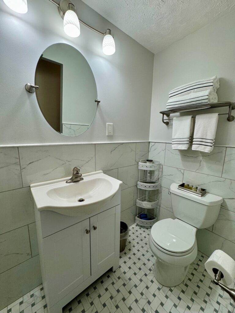 Clean bathroom with white fixtures and round mirror.
