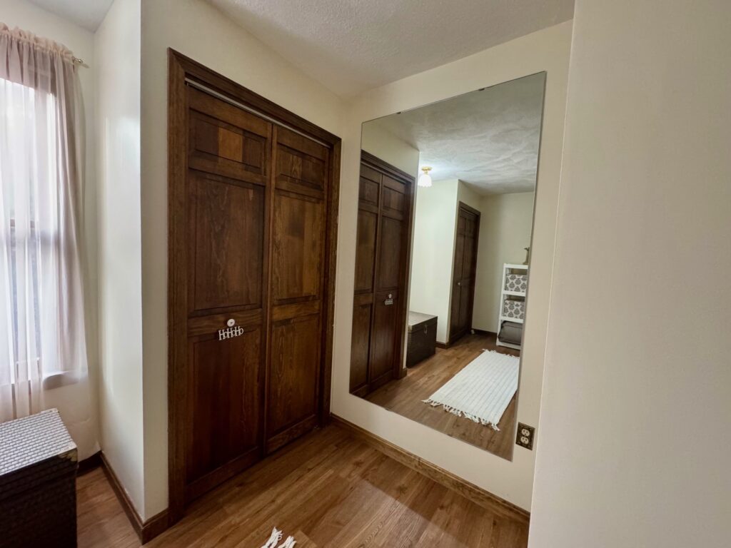 Hallway with wooden double doors and a large wall mirror.