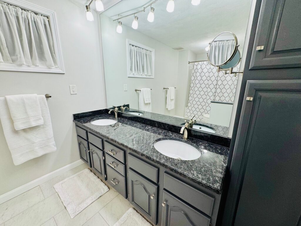 Modern bathroom with dark cabinetry and bright lighting.