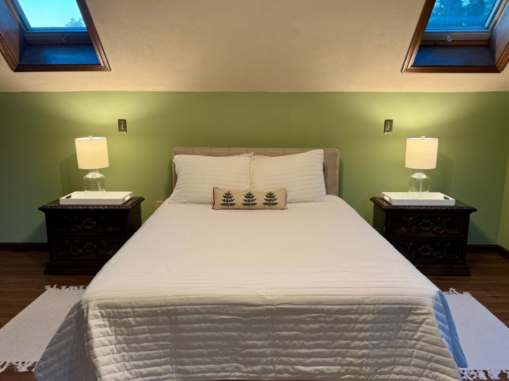 Cozy bedroom with a neatly made bed and green accent wall.